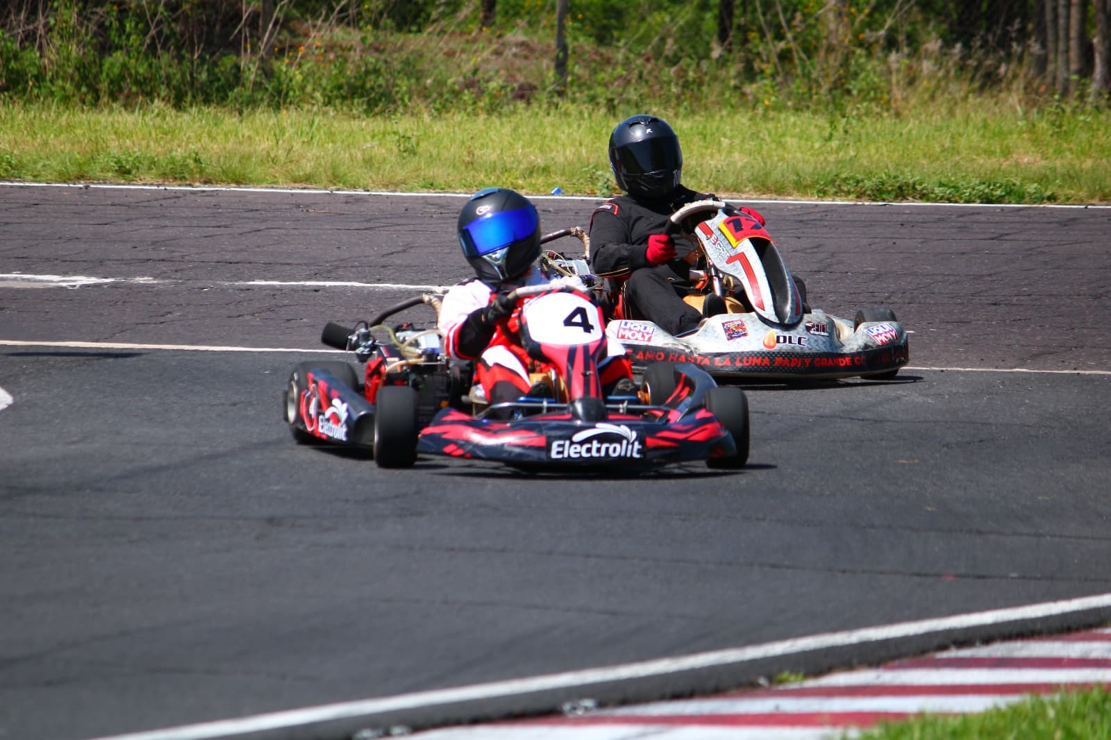 Karts disputando el apex de una curva con branding Electrolit y Liqui Moly